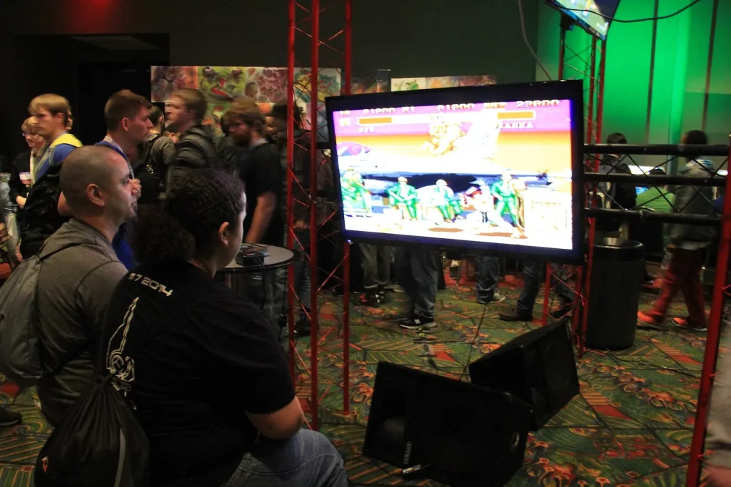 Players sitting together playing video games on a big screen at PAX South 2015