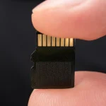 A microSD card held between two fingers
